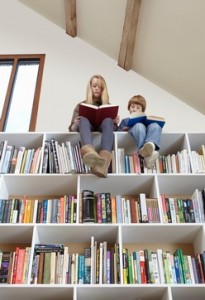 Children sitting on top of bookshelves